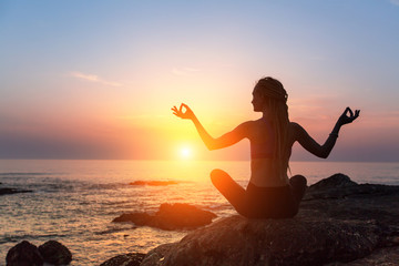 Yoga meditation silhouette. Healthy lifestyle. Fitness woman on the ocean during amazing sunset.