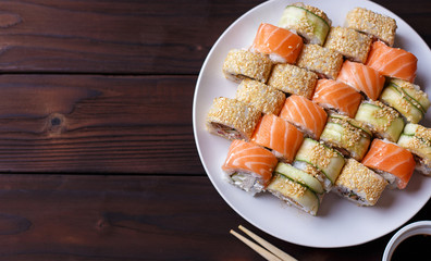 asty great colorful set of fresh japanese sushi maki rolls with salmon, tuna and avocado served on round plate,with chopsticks,flat lay. Food art, traditional seafood, restaurant menu photo