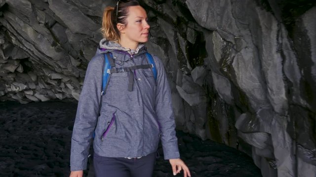 Woman exploring cave on Reynisfjara beach near Vik, Icealnd