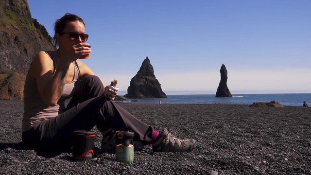 Woman having snack on Reynisfjara beach near Vik, Icealnd