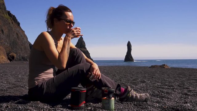 Woman having snack on Reynisfjara beach near Vik, Icealnd