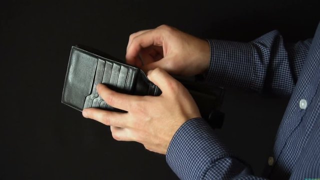 Taking Money Out of a wallet. The man opens a leather wallet and pulls out a 100 dollar bills. slow motion