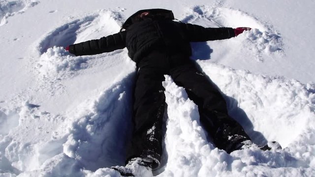 Young woman making snow angels