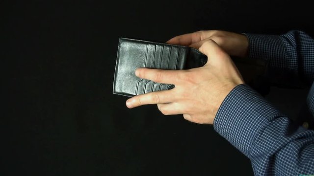 Taking Money Out of a wallet. The man opens a leather wallet and pulls out a 100 dollar bills. slow motion