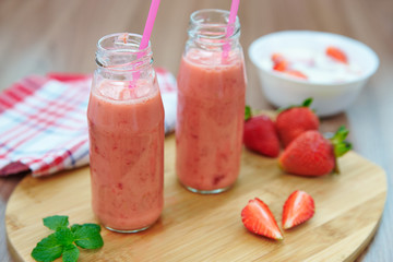 Strawberry smoothies and pieces of strawberries on a wooden board