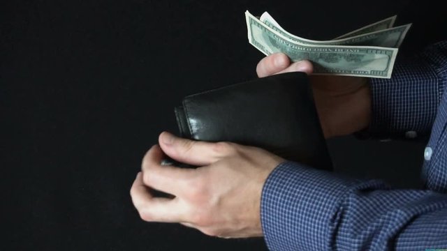 Taking Money Out of a wallet. The man opens a leather wallet and pulls out a 100 dollar bills. slow motion