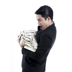 A side view of a young businessman carrying a large pile of money in his arms.
