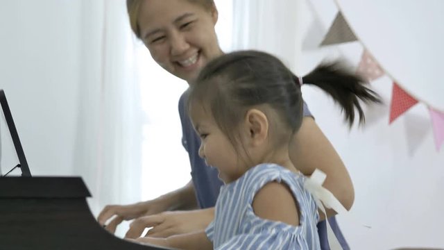 4K : Slow motion of Asian girl playing piano with her mother