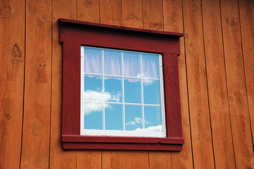 windows reflecting sky on wood wall of farm house