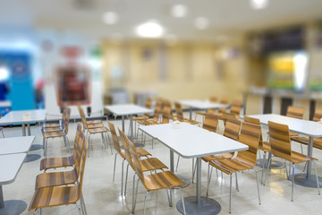 Blur of white table and wooden table on food court in shopping mall.
