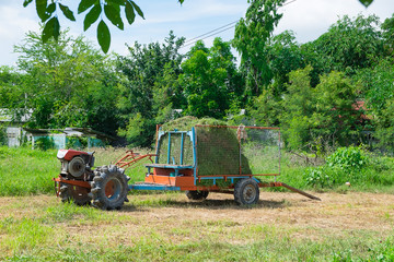 Old tractor with grass or hay on trailer. agriculture vehicle.