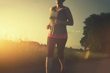 Photo sur Aluminium Jogging Frau joggt bei Sonnenuntergang