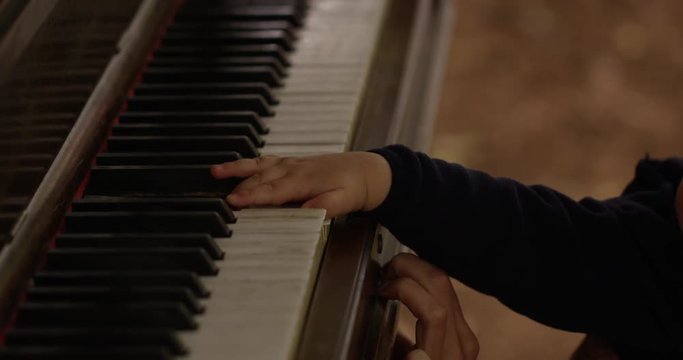 Infant hands pressing piano keys - slow motion up close