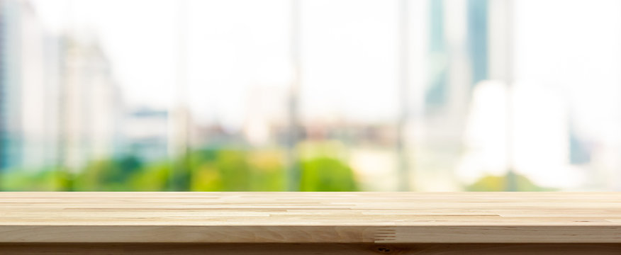 Wood table top on blur  city building view background looking through glass window, panoramic banner