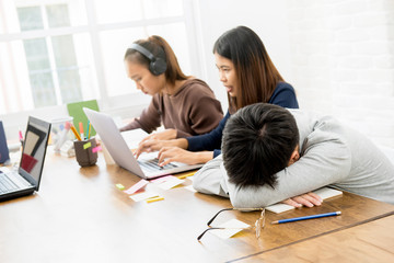 Group of students in co-working space with one student falling asleep at table