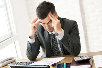 Serious businessman looking at financial document at working table