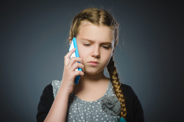 Obraz premium zdziwiona śliczna dziewczyna z telefonem komórkowym. pojedynczo na szaro