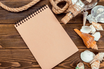 Shells and notepad on wooden table. Top view with copy space