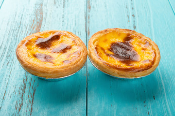 studio shoot of portuguese egg tarts at side view on a wood background