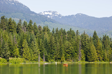 A small boat sits peacefully on a lake surrounded by trees and mountains