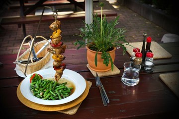 Pork meat with vegetable on skewer,beans with bacon, dining outdoor.