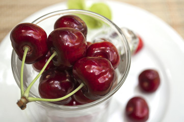 ripe cherry in a glass stands on a white plate