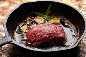 Raw beef steak on cast iron skillet