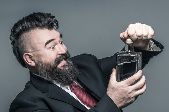 Adult bearded man in suit opening a bottle of alcohol