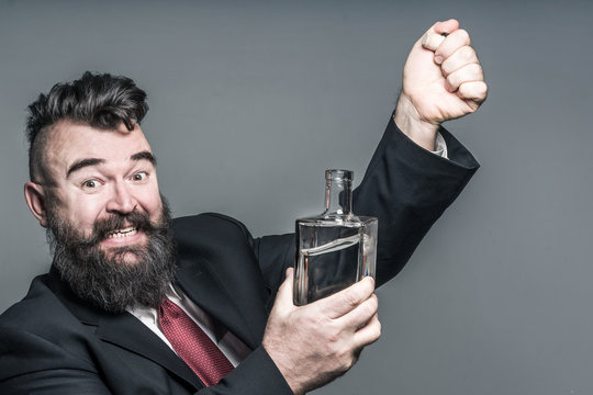 Adult bearded man in suit pulling a stopper from a bottle with alcohol