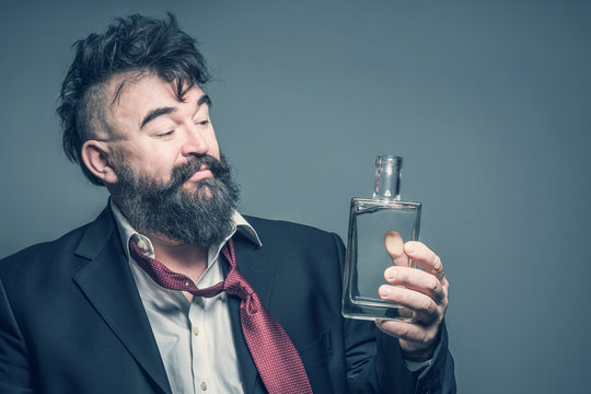 Adult bearded man in suit skeptical looks at the bottle of alcohol. Toned