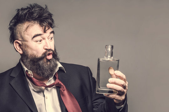 Boozy bearded man in suit talking with a bottle of alcohol on a brown background