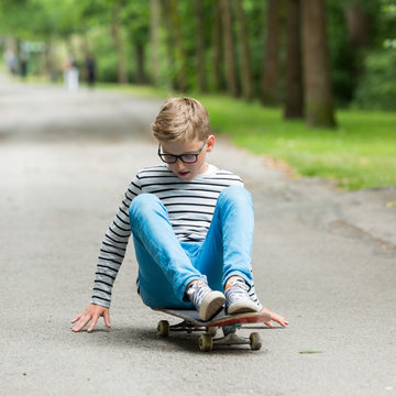 Jugendlicher / Kind / Heranwachsender spielt mit Skateboard / Fährt Skateboard