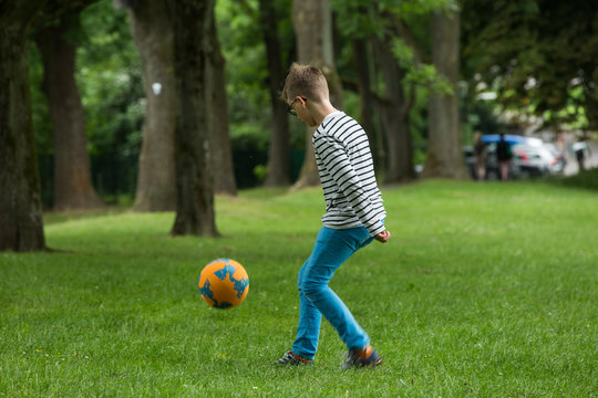 Jugendlicher / Heranwachsender / Junge / Kind spielt mit Fussball auf gr&uuml;ner Wiese / Wald