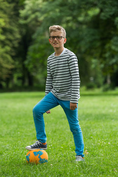 Jugendlicher / Heranwachsender / Junge / Kind spielt mit Fussball auf gr&uuml;ner Wiese / Wald