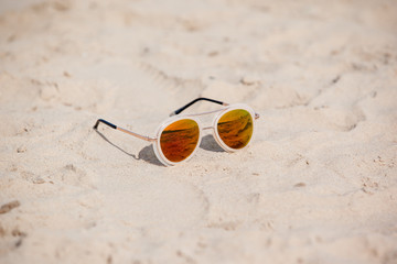 Fototapeta na wymiar Sunglasses on sandy beach in summer. Vacation background.
