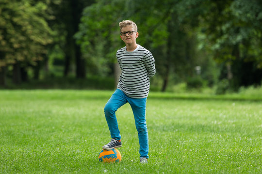 Jugendlicher / Heranwachsender / Junge / Kind spielt mit Fussball auf gr&uuml;ner Wiese / Wald