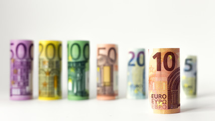 Gerollter 10 Euro Schein mit anderen Geldscheinen im Hintergrund