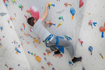 Obraz premium A successful man climbing on climbing wall. Teenage rock climber on boulders.