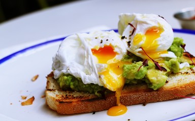 Poached egg with avocado on white plate
