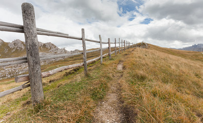 Fototapeta na wymiar Wooden fence long a path in Val di Funes