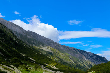 Beautiful view on the high green mountains peaks, on the blue sky background. Mountain hiking paradise landscape, no people.