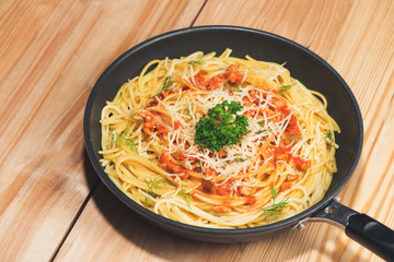Tasty spaghetti with tomato sauce and meat in pan on wooden table.