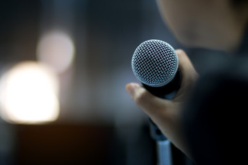 Blurred of businessman or speaker hand holding microphone for speech presentation in conference...