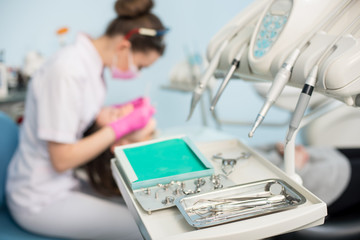 Different professional dental instruments, on the blurred background dentist is treating patient in...