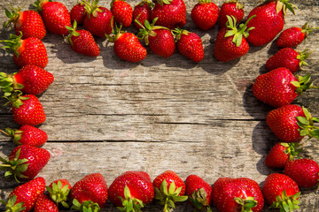 Frame of fresh red strawberries on wooden tabletop with copy space Top view