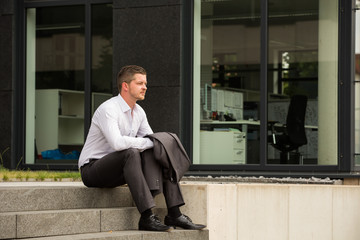 Business Mann sitzt auf Treppe und wartet / Pause / Termin / Kalender
