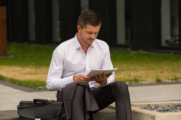 Business Mann sitzt auf Treppe und wartet / Pause / Termin / Kalender