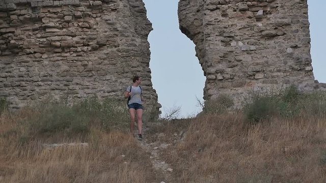 Smiling female tourist walking down the footpath and looking at ruins