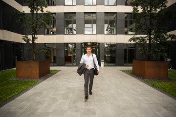 Fototapeta premium Business Mann / Herr verlässt Arbeitsgebäude / Feierabend / Termin