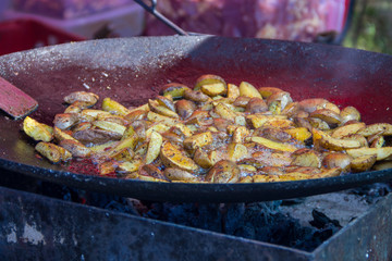 Roasted potatoes cooked outdoors in big metal cauldron pot. Street fast food